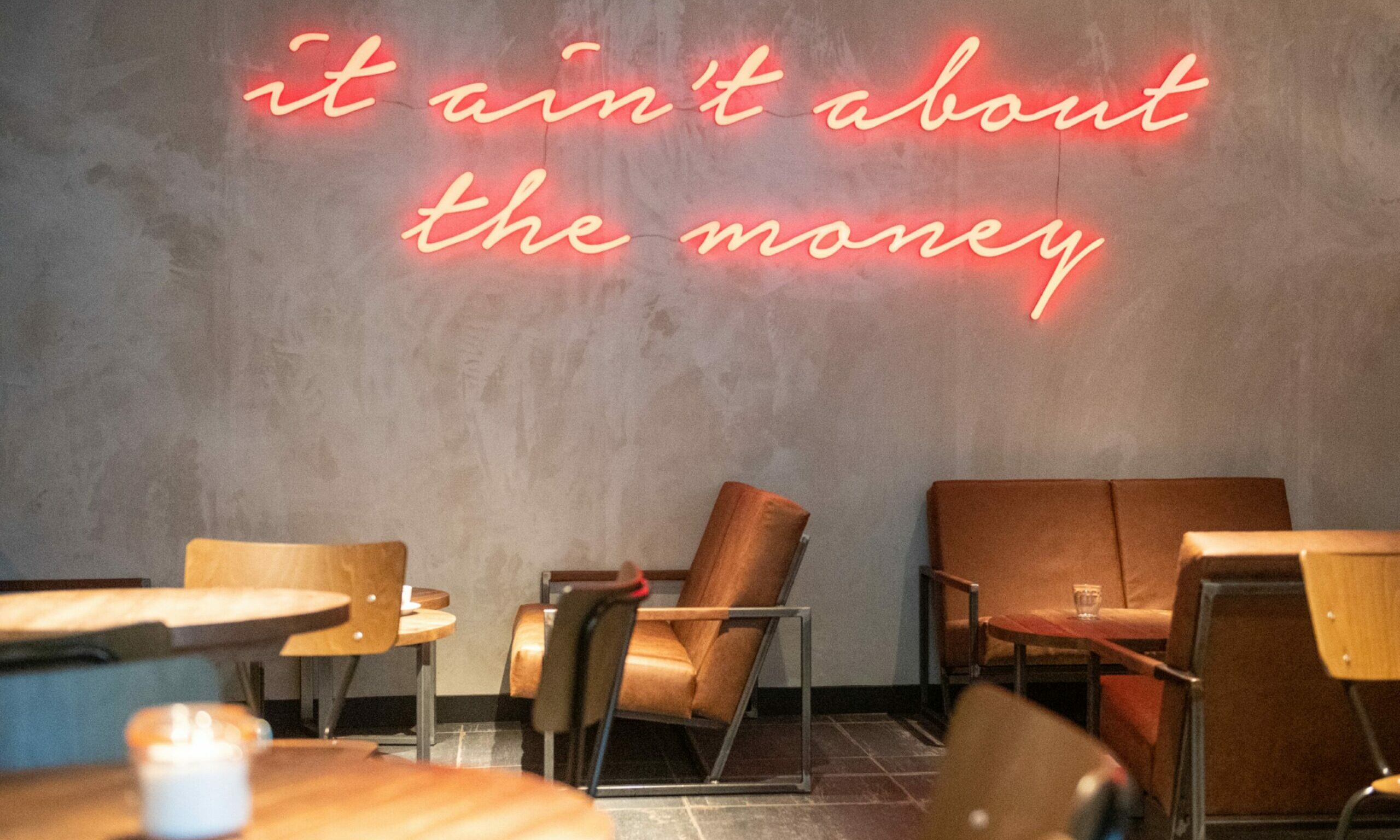 A sign on the Black Sheep Coffee wall in Aberdeenm stating "It ain't about the money"