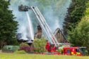Firefighters on an aerial platform dampen down the burnt-out house near Fochabers.