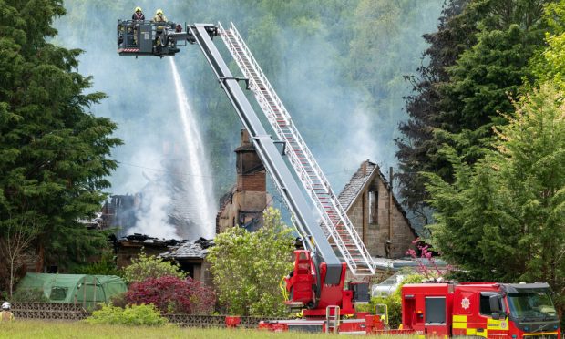 Firefighters on an aerial platform dampen down the burnt-out house near Fochabers.