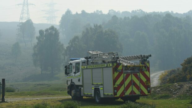 A community fire engine sits in a local field surrounded by woodland and thick fog.