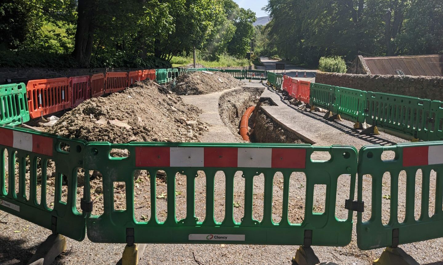 Fife Street completely blocked by barriers. Within barriers is long deep trench showing new pipe and mounds of rubble to left. 