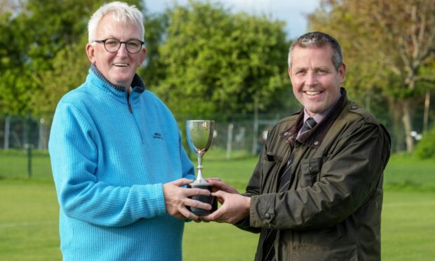 Shinty historian Dr Hugh Dan MacLennan presents Camanachd Association President, Steven MacKenzie with the Sutherland Cup player of the match trophy to be used in finals from 2023 onwards. Image supplied by Camanachd Association.