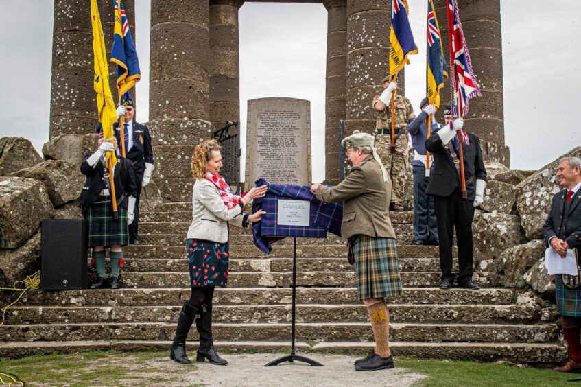 The Hon. Charles Pearson dressed in a kilt is pictured removing a cover from a plaque at the Stonehaven war memorial 