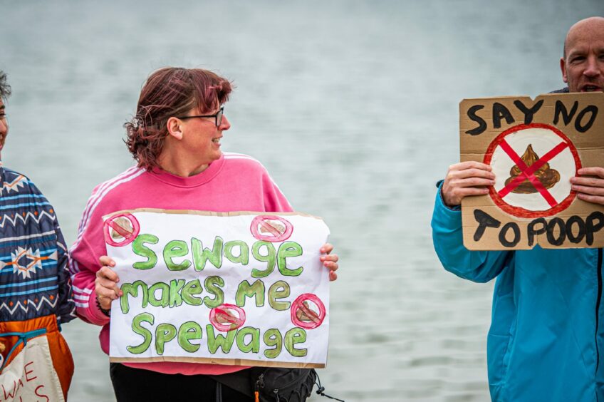 Protesters holding up signs that say "Sewage makes me spewage" and "Say no to poop"