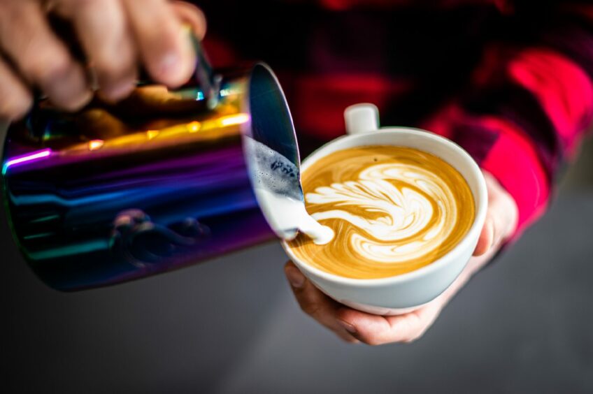 A barista at Figment creating latte art