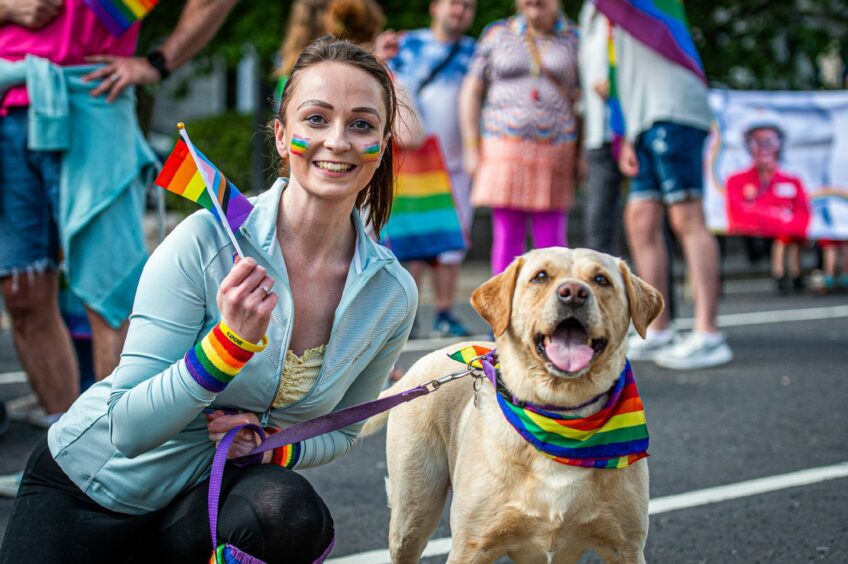 Woman sporting rainbow face paint with dog in a rainbow bandanna at Grampian Pride 2023 in Aberdeen.