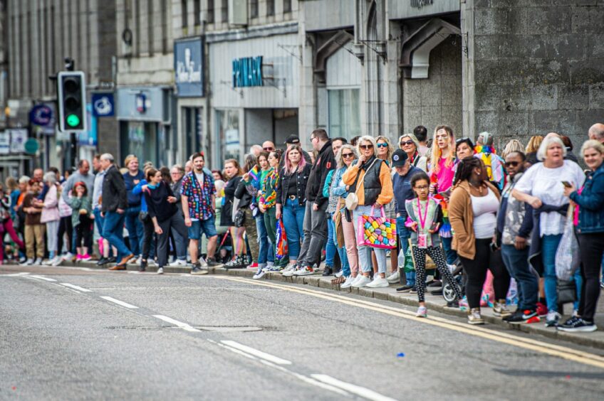 Streets lined with people as the Grampian Pride parade passes by.