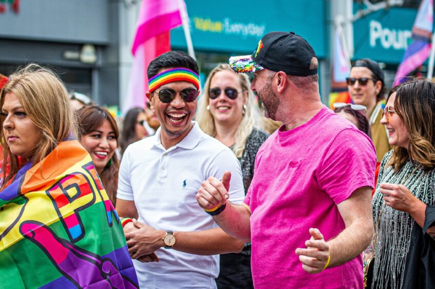 Smiling revellers in rainbow gear.