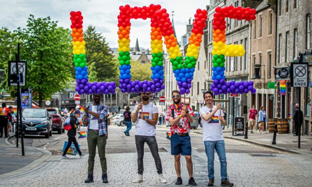 Four men hold up the rainbow lletters spelling Love at last year's Grampian Pride