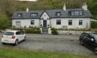 The Ferry Inn in Uig - which is a small one story building with four letting rooms. Two cars are outside the building.