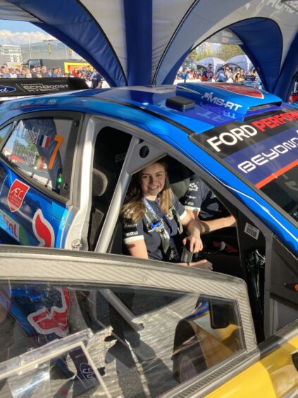 Emily Easton-Page pictured in the passenger seat of a blue rally car. 