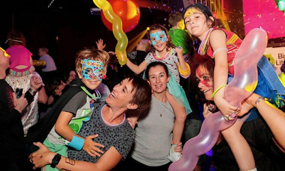 Parents and children at a Big Fish Little Fish family rave event with balloons and superhero masks. 