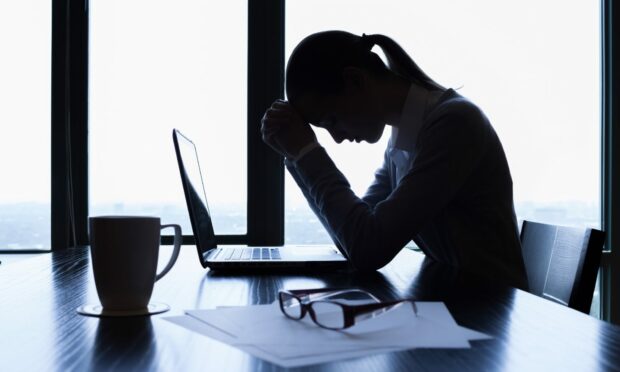 Woman sitting at desk looking stressed.