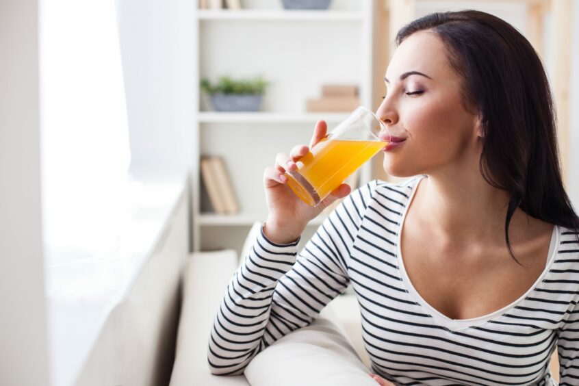 Woman drinking a glass of orange juice.