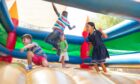 Children bouncing on a colourful bouncy castle