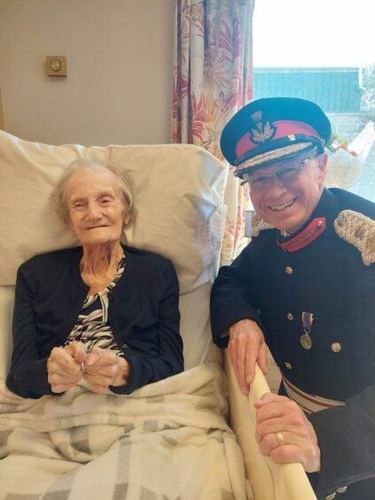 Elizabeth Bonner smiling with Lord Lieutenant of Banffshire, Andrew Simpson on her 100th birthday at Glenisla care home. 