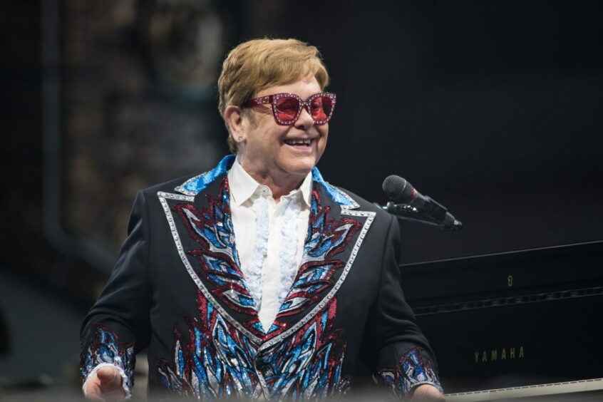 Elton John smiling while on stage.