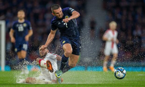 Scotland's John McGinn is tackled by Georgia's Lasha Dvali on the soaked pitch at Hampden.