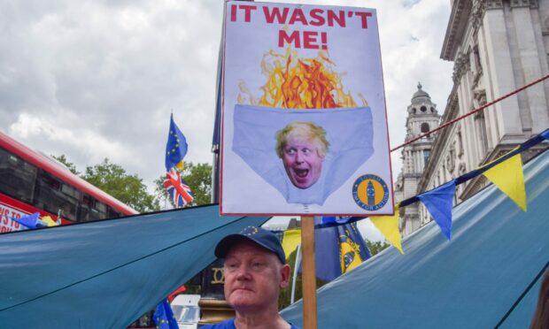 A protester holds a sign mocking Boris Johnson as anti-Tory and anti-Brexit activists stage their weekly protest in Westminster. Image: Vuk Valcic/ZUMA Press Wire/Shutterstock.