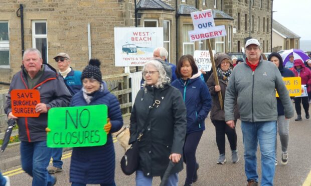 Campaigners marching on Harbour Street in Hopeman holding banners calling for the GP surgery to be kept open.