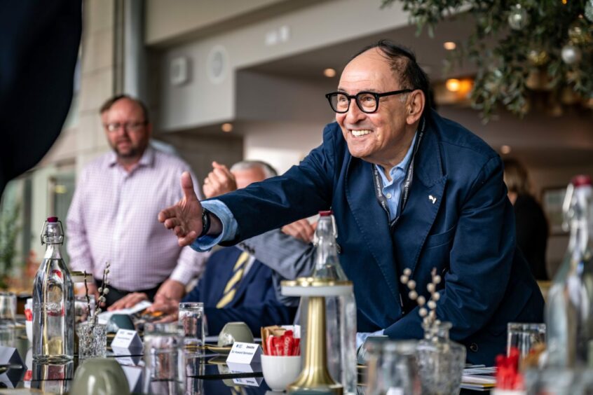 Sir Howard Bernstein holding his hand out over a table