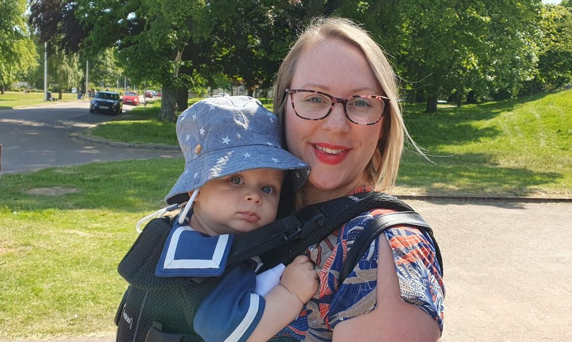 Krissy Martin with Teddy in a harness against her chest outside Elgin Library 