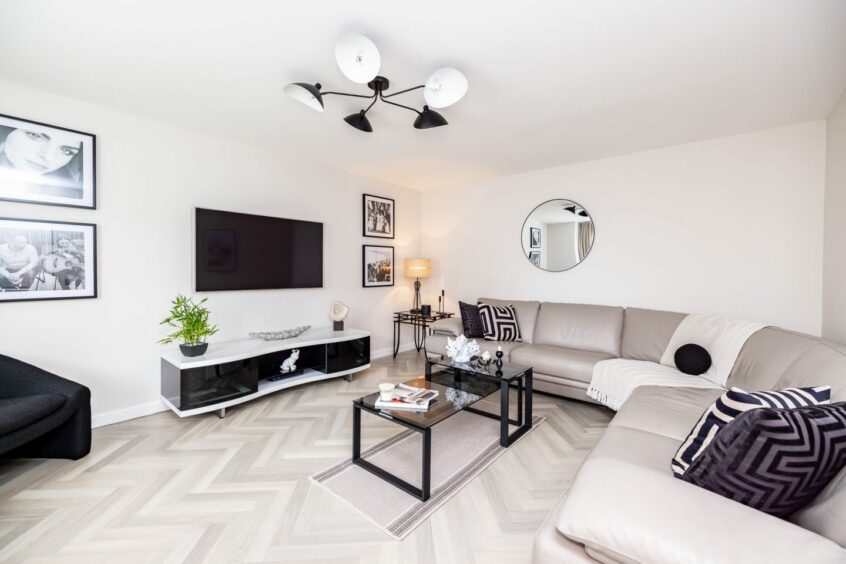 Stylish sitting area with light herringbone flooring and minimalist decor.