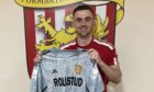 New Formartine United goalkeeper Jake Ritchie is pictured in front of the club badge holding a match top.