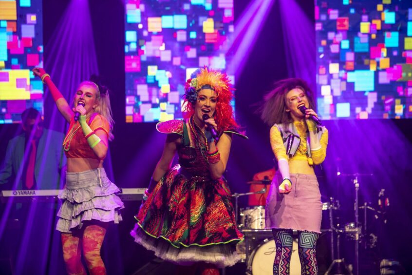 Electric Dreams singers on stage in 80s inspired outfits.