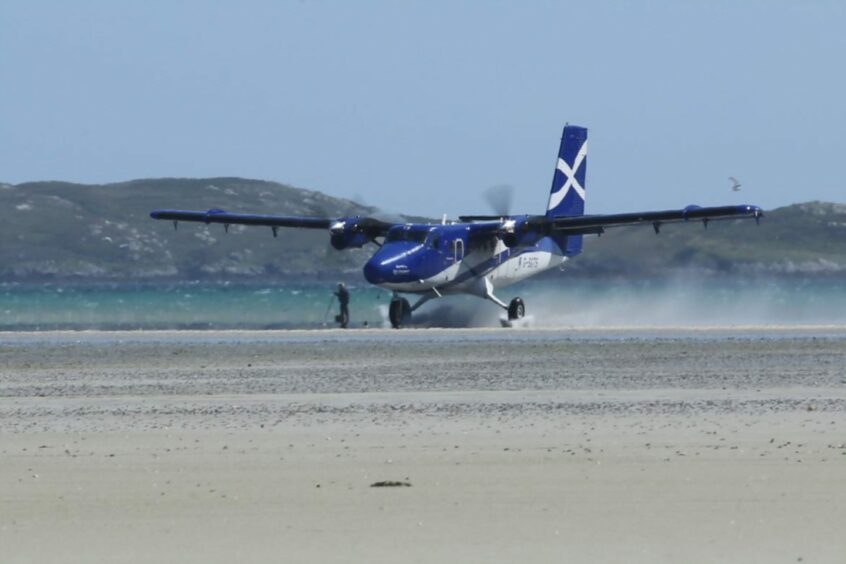 Loganair plane landing at Barra Airport.