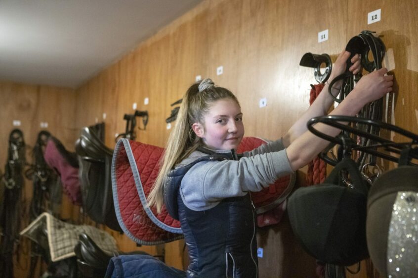 Equine degree student hanging up saddle