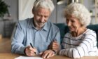 elderly couple signing a document