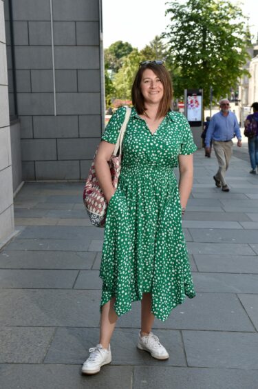 Woman in a green summer dress styled with white trainers.