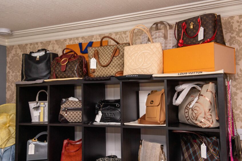 Shelf of designer handbags including Chanel and Louis Vuitton.