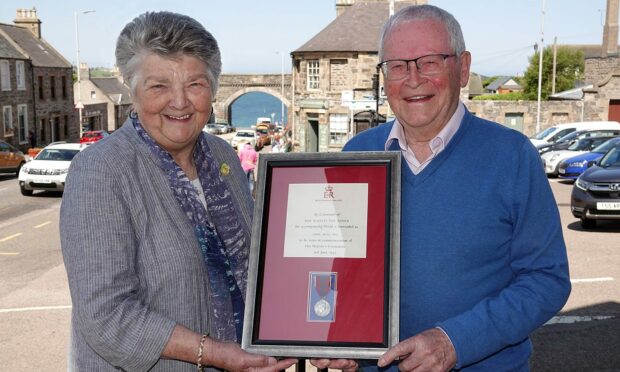 Joe Mowat presents his father's Queen Elizabeth coronation medal to Cullen, Deskford and Portknockie Heritage Group president Brenda Wood. Image: Colin Shearer
