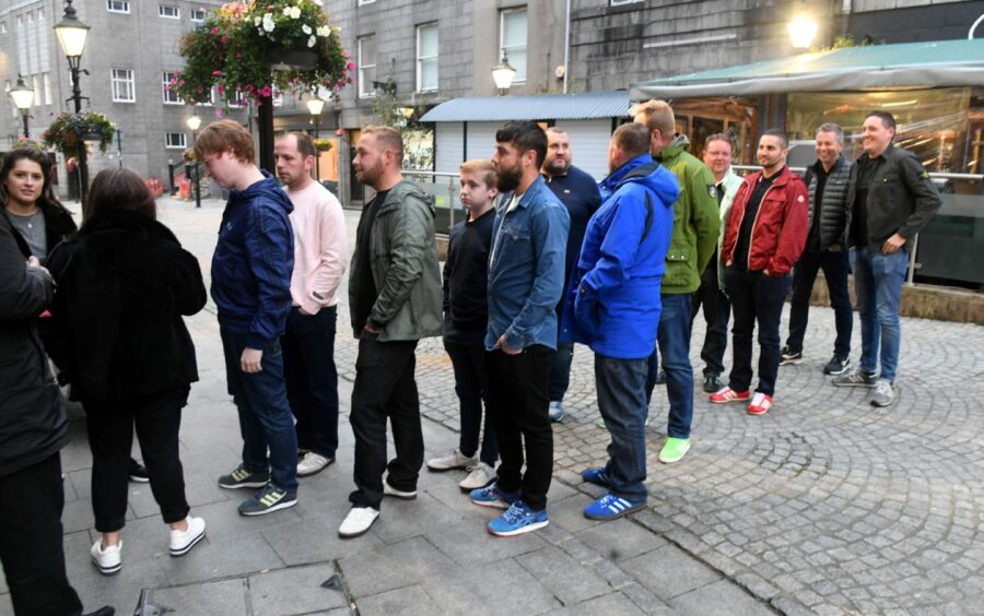 People queuing on The Green in Aberdeen outside the Hanon store. 