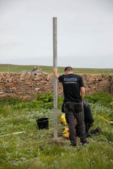 Engineers dressed in black work to install a post on the grounds of the island's primary school. 