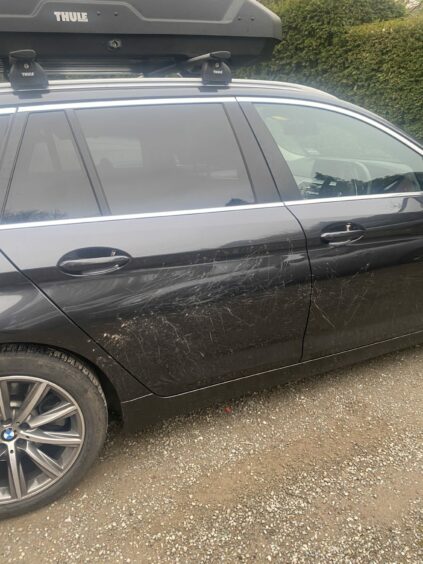 A black BMW estate with scratches down the driver side caused by a peacock. There are also dents on the back passenger door.