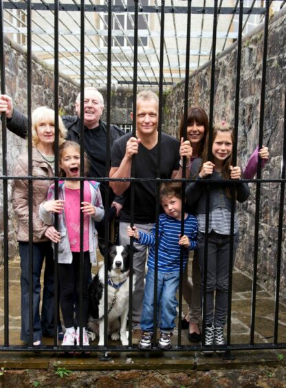 Group of tourists smiling perhaps too gleefully while touring Inveraray Jail.