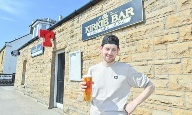 Danny Grant standing outside the front of the Kirkie with a pint of Tennent's.