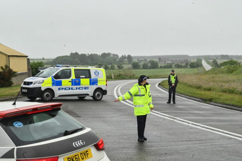 A police officer standing on the road diverting traffic.