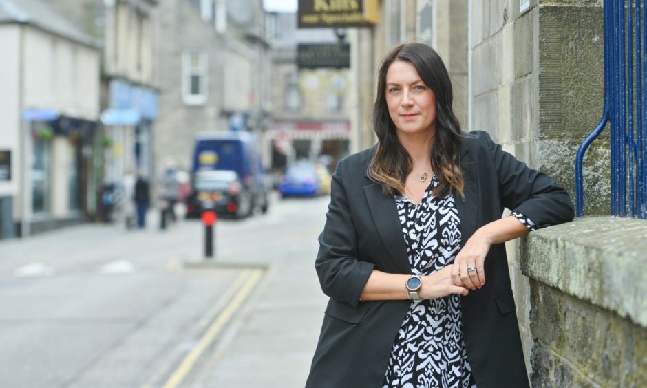 Sarah Medcraf leaning against wall on South Street in Elgin.