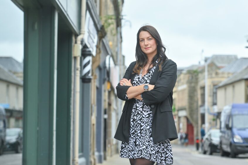 Sarah Medcraf with arms folded in Elgin town centre street.