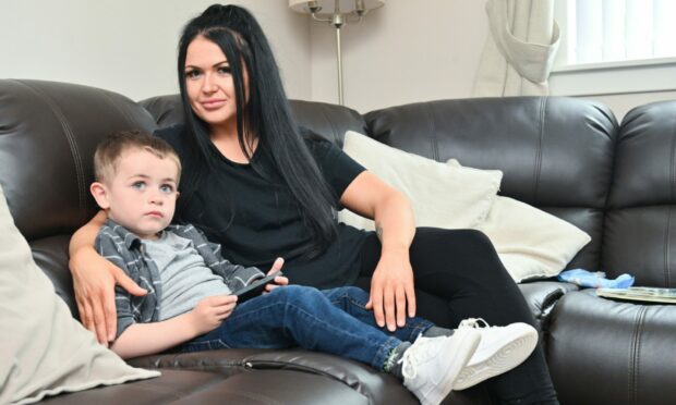 Chelsea Findlay with her arm round Arran as they sit on sofa together side-on to camera.