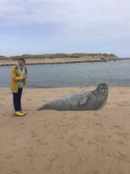 Jessica Reid wearing a yellow jacket on the beach with her virtual reality seal 
