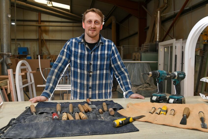 Roberts standing at a workshop table with his tools
