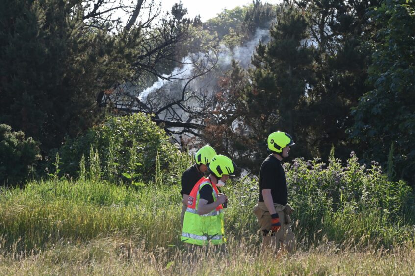 Firefighters are seen walking near the scene of the fire. 