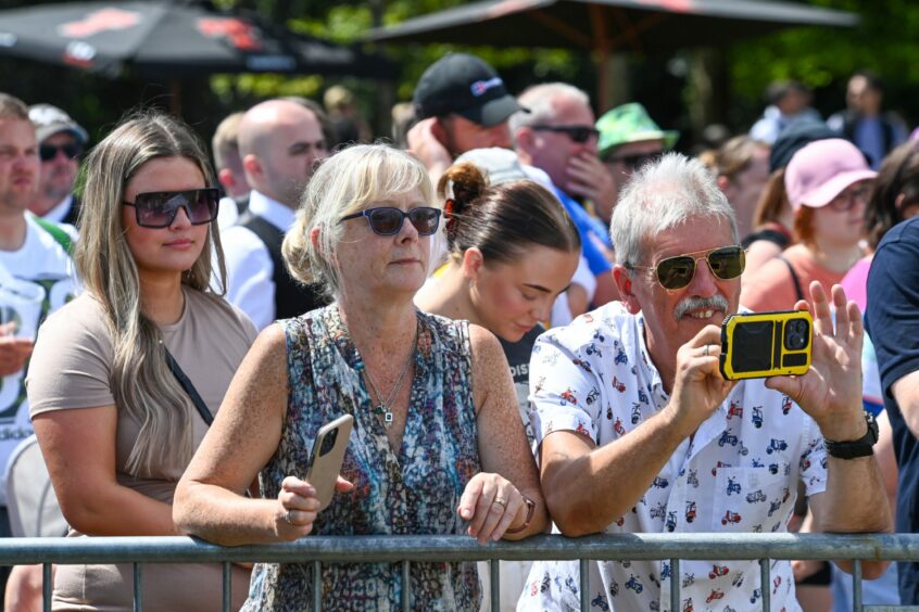 Fan takes photos of pipe band performance.