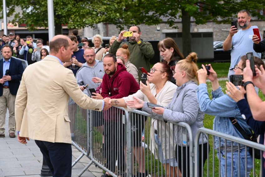 Prince William greets crowds of people.