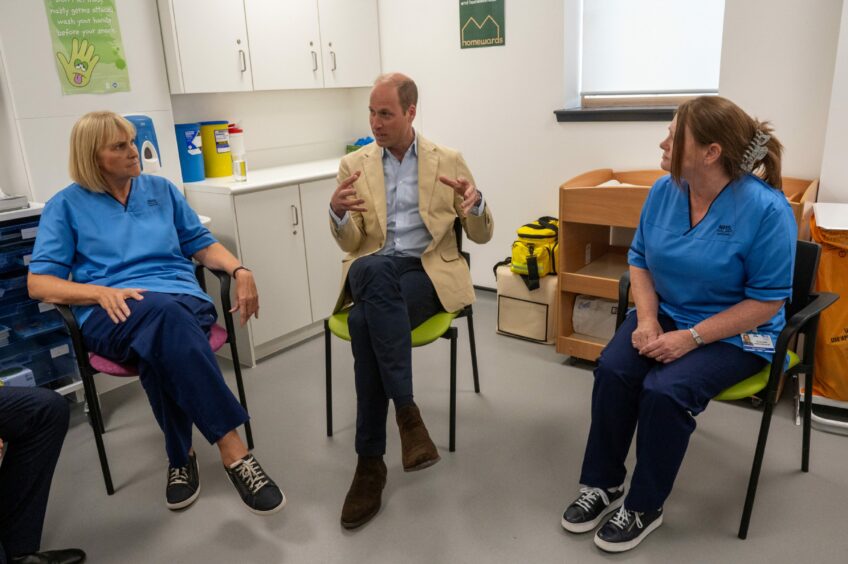 Prince William sitting beside a nurse on either side.